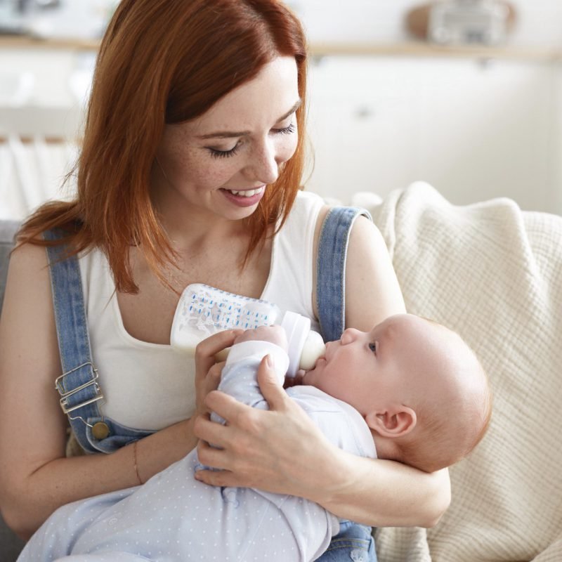 Moeder geeft baby fles met zuigelingenvoeding