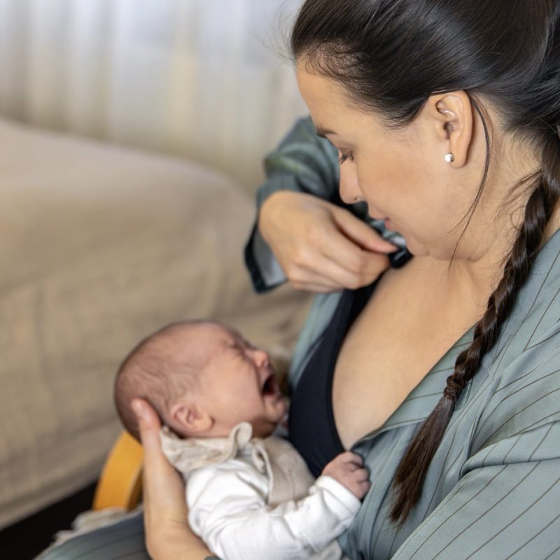moeder die haar baby borstvoeding geeft terwijl ze ontspannen en gerust lijkt