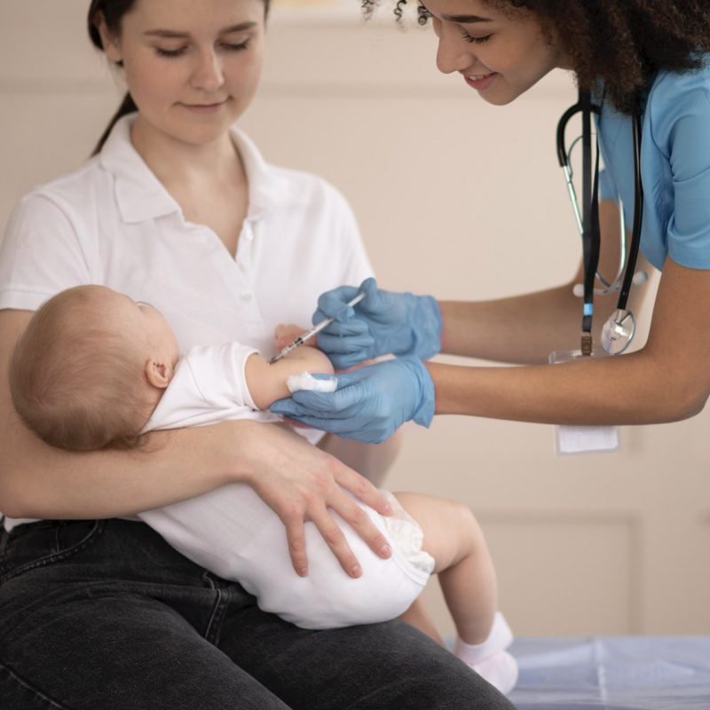 Zorgverlener vaccineert baby terwijl moeder hem vasthoudt